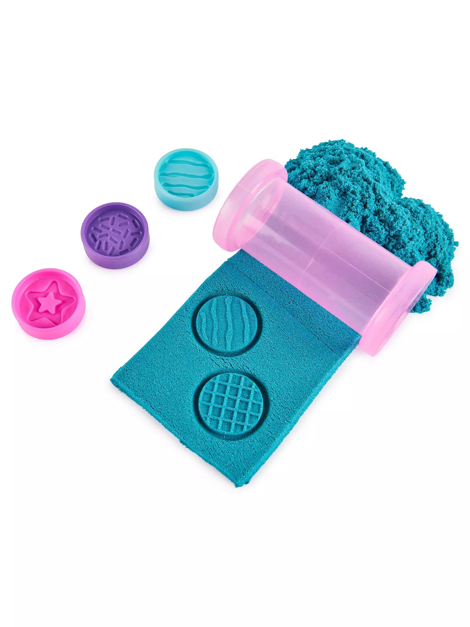 Colorful sand toys including a pink roller, blue molds, and a green sand box on a white background.